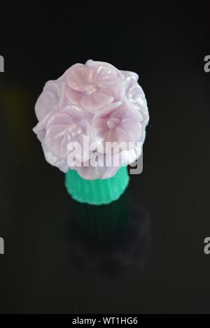 Wunderschöner Blumenstrauß aus violetter Seife, sehr originell und wunderschön. Handgefertigte Seife auf einer schwarzen glänzenden Oberfläche. Stockfoto