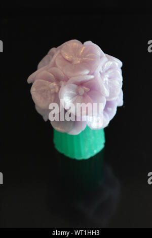 Wunderschöner Blumenstrauß aus violetter Seife, sehr originell und wunderschön. Handgefertigte Seife auf einer schwarzen glänzenden Oberfläche. Stockfoto