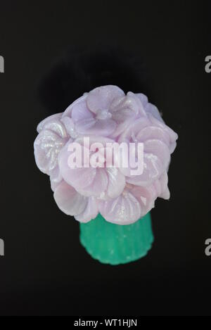 Wunderschöner Blumenstrauß aus violetter Seife, sehr originell und wunderschön. Handgefertigte Seife auf einer schwarzen glänzenden Oberfläche. Stockfoto