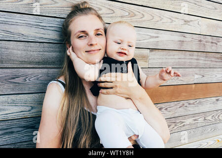 Junge Mutter umarmt Baby Stockfoto