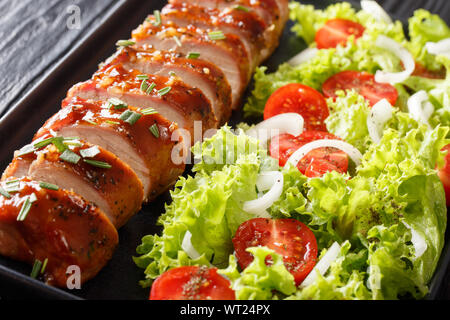 Gebackenes Schweinefilet in Honig - Knoblauch Sauce mit frischen Salat close-up auf einem Teller auf den Tisch. Horizontale Stockfoto