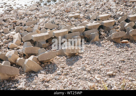 Betonsteine oder Wellenbrecher, der am Ufer des Meeres oder konkrete schwere Strukturen am Ufer. Stockfoto