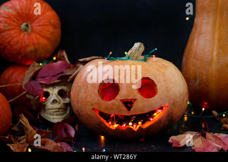 Halloween kreative Komposition mit einem Schädel und ein Scary Pumpkin auf dunklem Hintergrund, Nahaufnahme, horizontale Ausrichtung Stockfoto