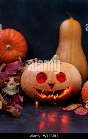 Halloween kreative Komposition mit einem Schädel und ein Scary Pumpkin auf dunklem Hintergrund, Nahaufnahme, vertikale Ausrichtung Stockfoto