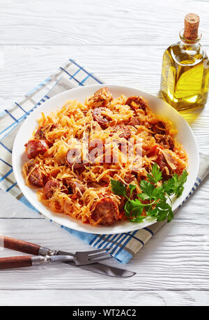 Kohleintopf mit in Scheiben geschnittenen gegrillte Würstchen auf einem weißen Teller auf einen hölzernen Tisch serviert, vertikale Ansicht von oben Stockfoto