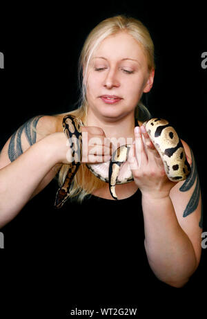 Portrait von Mädchen mit Royal Python Schlange. Schöne Frau hält Schlange in der Hand und vor der Kamera posieren. Stockfoto