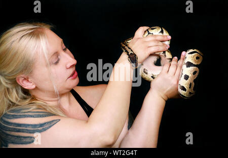 Portrait von Mädchen mit Royal Python Schlange. Schöne Frau hält Schlange in der Hand und vor der Kamera posieren. Stockfoto