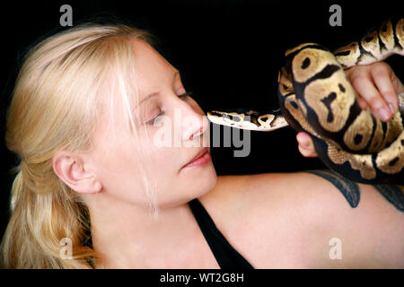 Portrait von Mädchen mit Royal Python Schlange. Schöne Frau hält Schlange in der Hand und vor der Kamera posieren. Stockfoto