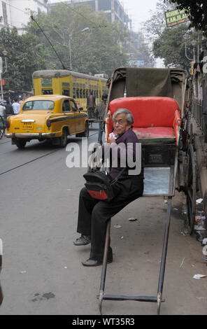 Ein Mann steht auf einer Hand gezeichnete Karre auf College Street in Kalkutta, Indien. Kalkutta ist eine Metropole mit einer sehr begrenzten Straße Raum und einer der höchsten Ve Stockfoto