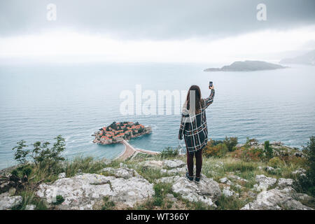 Ein Mädchen touristische oder ein blogger nimmt eine selfie oder Fotos oder Videos von einer schönen Aussicht in Montenegro. Stockfoto