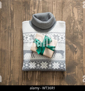 Weihnachtsgeschenk mit Green Ribbon und grauen pullover mit christmas Ornament auf Holz- Oberfläche. Ansicht von oben. Weihnachten Konzept. Stockfoto