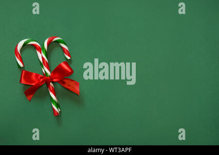 Weihnachten Zuckerstangen mit roter Schleife auf grünem Hintergrund. Kopieren Sie Platz. Ansicht von oben. Stockfoto
