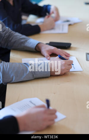 Die Hände von Menschen, die Fragebögen in Papierform ausfüllen Stockfoto