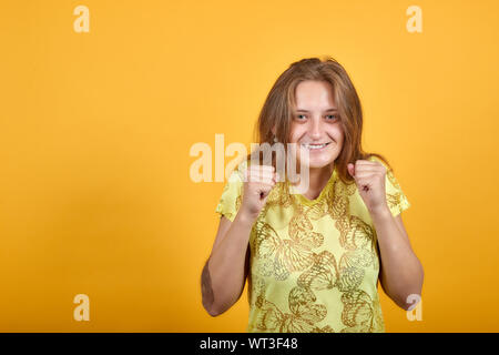 Brunette Mädchen in gelben T-Shirt über isolierte orange Hintergrund zeigt Emotionen Stockfoto