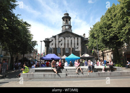 Die Menschen in der Sonne auf dem Marktplatz und das Stadtmuseum in Lancaster am Markttag. Stockfoto