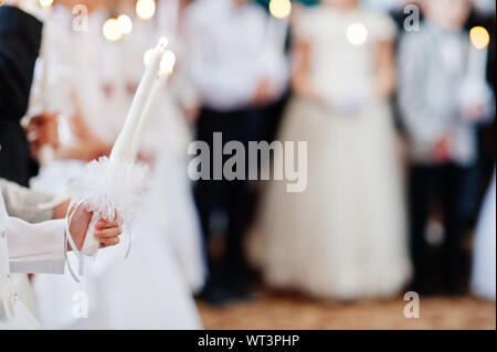 Junge Mädchen in Weiß halten Sie die Kerze in der Hand auf die erste heilige Kommunion. Stockfoto