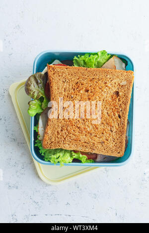 Gesunde Sandwich mit grünen, Schinken, Tomaten und Käse in Kunststoff verpackt sein. Essen zum Mitnehmen für Mittagessen in der Schule oder bei der Arbeit. Stockfoto