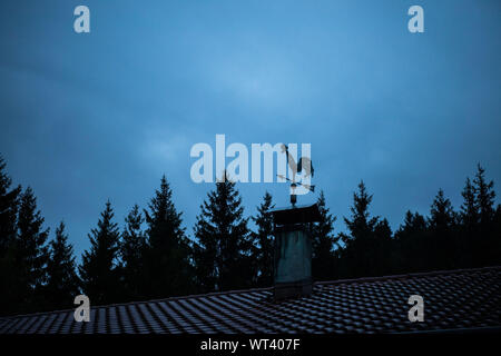 Bad Hindelang, Deutschland. 11 Sep, 2019. Ein wetterhahn steht auf einem Dach vor bewölkter Himmel bei Sonnenaufgang. Credit: Lino Mirgeler/dpa/Alamy leben Nachrichten Stockfoto