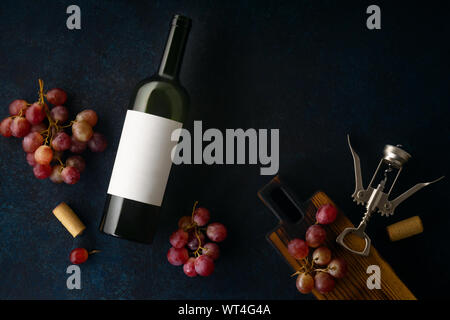 Flatlay mit einer Flasche Rotwein, Korken und roten Trauben auf blauem Hintergrund mit Kopie Raum Stockfoto