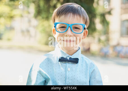 Portrait von Clever Happy Boy in Gläsern in Shirt und Schmetterling. Zum ersten Mal in die Schule. Zurück zu Schule. Smart wenig Schüler. Konzept des Lernens, Sch Stockfoto