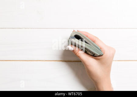 Blick von oben auf die weibliche Hand mit einem pack Geld für Holz- Hintergrund. Hundert Dollar. Geschäftskonzept. Nächstenliebe und Tipps Konzept. Stockfoto