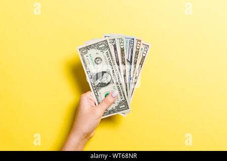 Blick von oben auf die weibliche Hand geben verschiedene Dollarnoten auf farbigen Hintergrund. Nächstenliebe und spende Konzept. Stockfoto