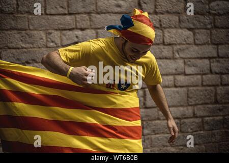 Barcelona, Spanien. 11 Sep, 2019. Eine Pro-unabhängigkeit Aktivist schreibt sich selbst in einem riesigen katalanischen Flagge auf nationalen Katalonien's Day, 'La iada' Credit: Matthias Oesterle/Alamy leben Nachrichten Stockfoto