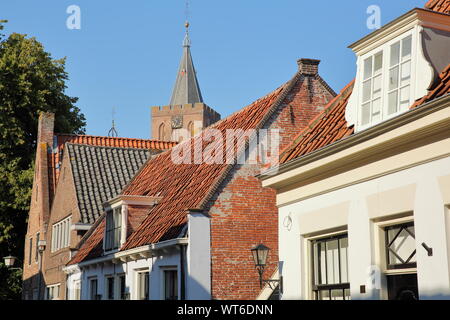 Historische Häuser innerhalb der Festungsstadt Naarden, Niederlande, mit dem Glockenturm der Grote Kerk Kirche im Hintergrund Stockfoto