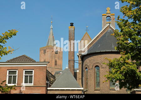 Historische Häuser innerhalb der Festungsstadt Naarden, Niederlande, mit dem Glockenturm der Grote Kerk Kirche im Hintergrund Stockfoto