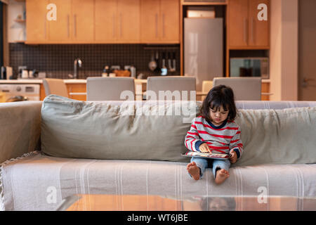 Süße kleine Mädchen sitzen auf Ihrem Sofa mit einem Tablet Stockfoto