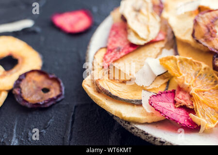 Gesunde hausgemachte Frucht Chips von Apple, Orange, Banane, Erdbeere auf dunklem Hintergrund. Bio Diät essen. Die vegane Ernährung. Getrocknete Früchte. Vegetarische pl Stockfoto