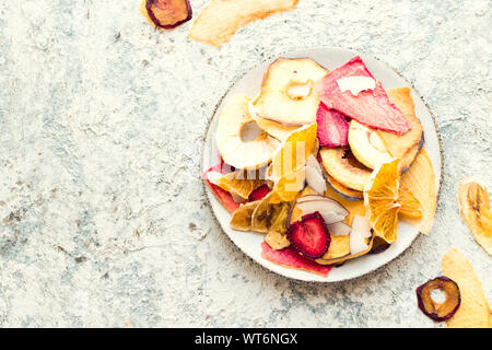 Gesunde hausgemachte Frucht Chips von Apple, Orange, Banane, Erdbeere auf grauem Hintergrund. Bio Diät essen. Die vegane Ernährung. Getrocknete Früchte. Vegetarische pl Stockfoto