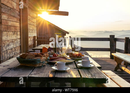 Frühstück im rustikalen hölzernen Terrasse Terrasse einer Hütte hutte in Tirol alm bei Sonnenaufgang Stockfoto