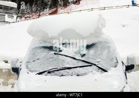 Auto auf einer Straße mit großen dicken Schneeschicht bedeckt nach starkem Schneefall. Extreme blizzard Nachwirkungen. Fahrzeug Windschutzscheibe mit gefrorenen Fenster und Scheibenwischer Stockfoto