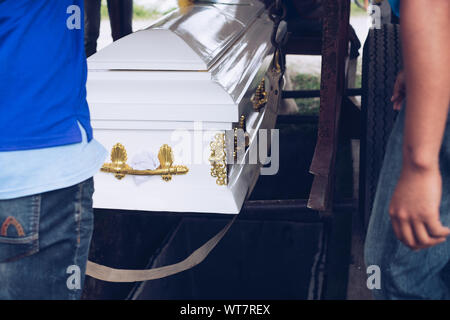 Pallbearers sorgfältig den Prozess der Senkung der Schatulle auf den Boden für die Verstorbenen an seinen endgültigen Ort der Ruhe beaufsichtigen, während der Beerdigung Stockfoto