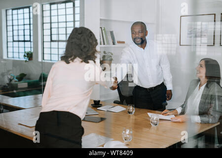 Lächelnd manager Händeschütteln mit einem Kollegen in einem Büro Stockfoto