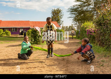 Imani Junior Academy, Nanyuki, Laikipia County, Kenia - Juni 13., 2019: Offene Foto der jungen Schüler überspringen mit einem improvisierten Seil o Stockfoto