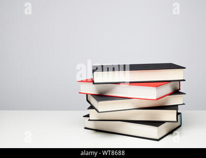 Stapel von vier schwarze und eine rote gebundene Bücher auf einem Tisch Stockfoto