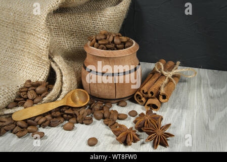 Kaffeebohnen überlaufen von einem kleinen Topf, würzige, Sternanis und Zimtstangen in einem rustikalen noch Leben auf einem Holztisch mit Platz kopieren Stockfoto