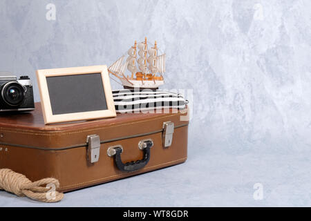 Altmodische leder Koffer, Bilderrahmen mit leeren schwarzen Platz für Text, Segelboot Spielzeug, retro Foto Kamera, Seil. Kleidung und persönliche Accessori Stockfoto