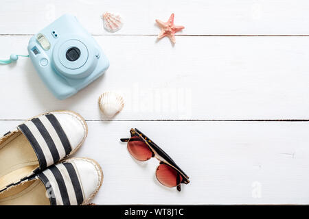 Sommerurlaub Zusammensetzung, traveler Zubehör auf weißem Schreibtisch aus Holz: Sonnenbrillen, Sandalen, instant Kamera, sea shell und Stern. Urlaub, entspannen, se Stockfoto