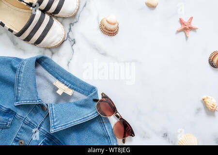 Jeans Jacke, Flasche Parfüm und retro altmodischen Sonnenbrille auf Marmor Hintergrund. Flach design Zusammensetzung mit weiblicher Kleidung und Zubehör Stockfoto