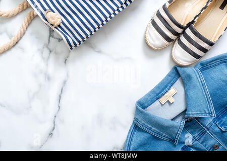 Grenze der gestreifte Schuhe, Jeans Jacke, Sommer Tasche auf Marmor Hintergrund. Trendige flach Zusammensetzung, lässige Kleidung von Schönheit Fashion Blogger Stockfoto