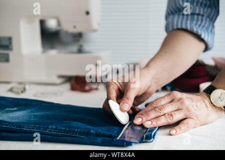 Näherin Kennzeichnung Saum auf ein Paar Jeans in Schneiderei Stockfoto