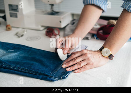 Näherin Kennzeichnung Saum auf ein Paar Jeans in Schneiderei Stockfoto