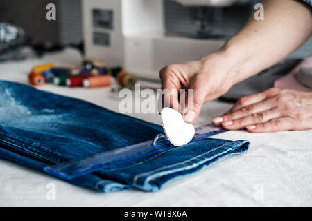 Näherin Kennzeichnung Saum auf ein Paar Jeans in Schneiderei Stockfoto