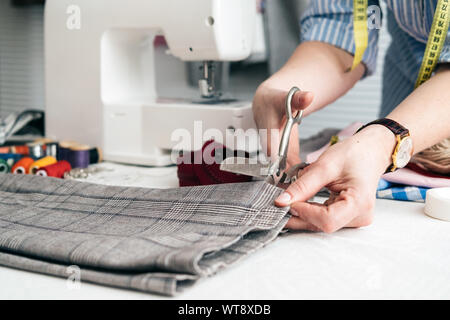 Maßgeschneiderte jeans Schneiden mit einer Schere in der Werkstatt Stockfoto