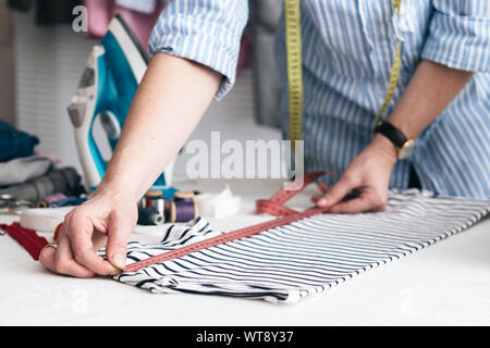 Junge Frau mit Maßband in Schneiderei Arbeiten Stockfoto