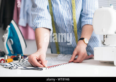 Junge Frau mit Maßband in Schneiderei Arbeiten Stockfoto