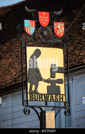 Burwash Ortsschild entlang der High Street mit einem weald ironworker, Burwash, East Sussex, England, Vereinigtes Königreich, Europa Stockfoto